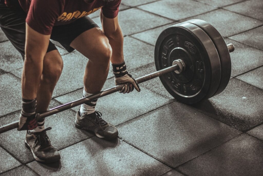 Person lifting a barbell in a gym, illustrating higher-level loading during rehabilitation